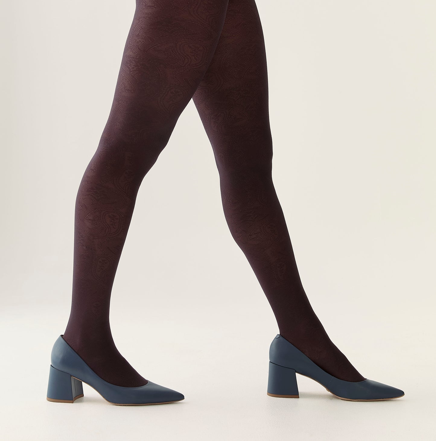 Person wearing black tights and blue shoes on a light background