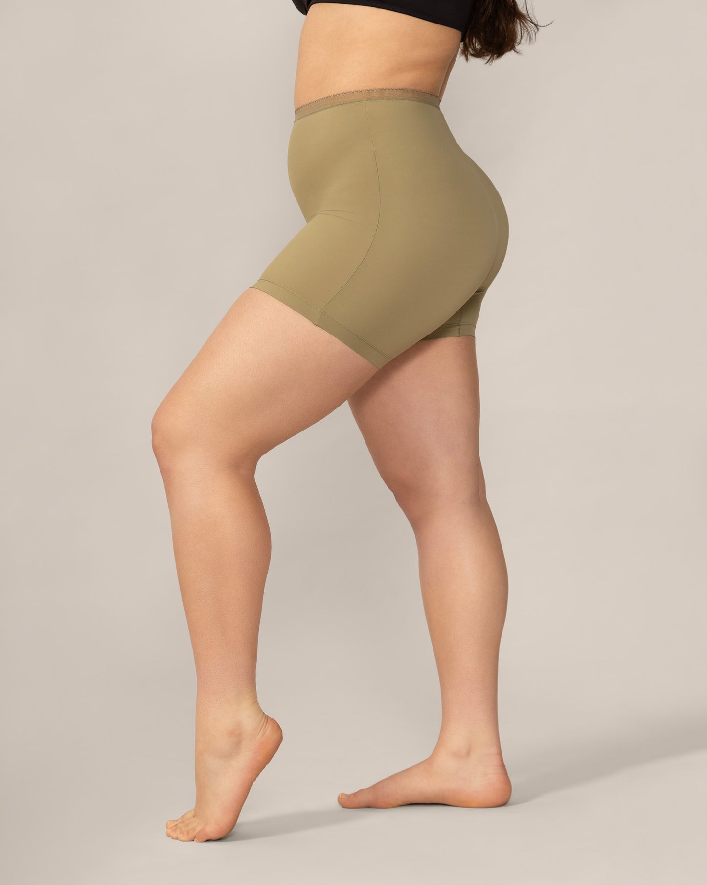 Person wearing olive green anti chaffing shorts on a plain background