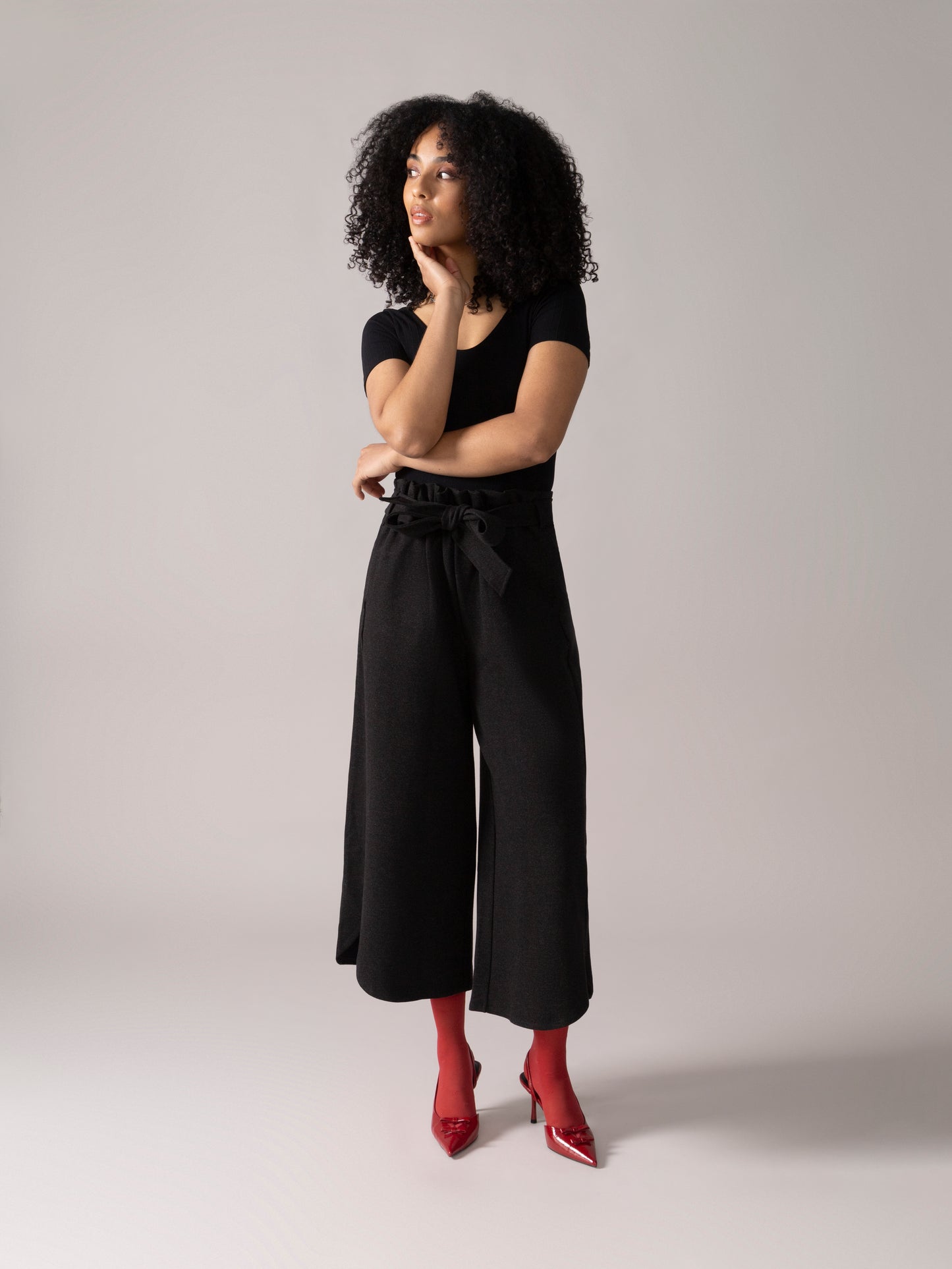 Woman wearing a black bodysuit with wide-leg pants and red socks